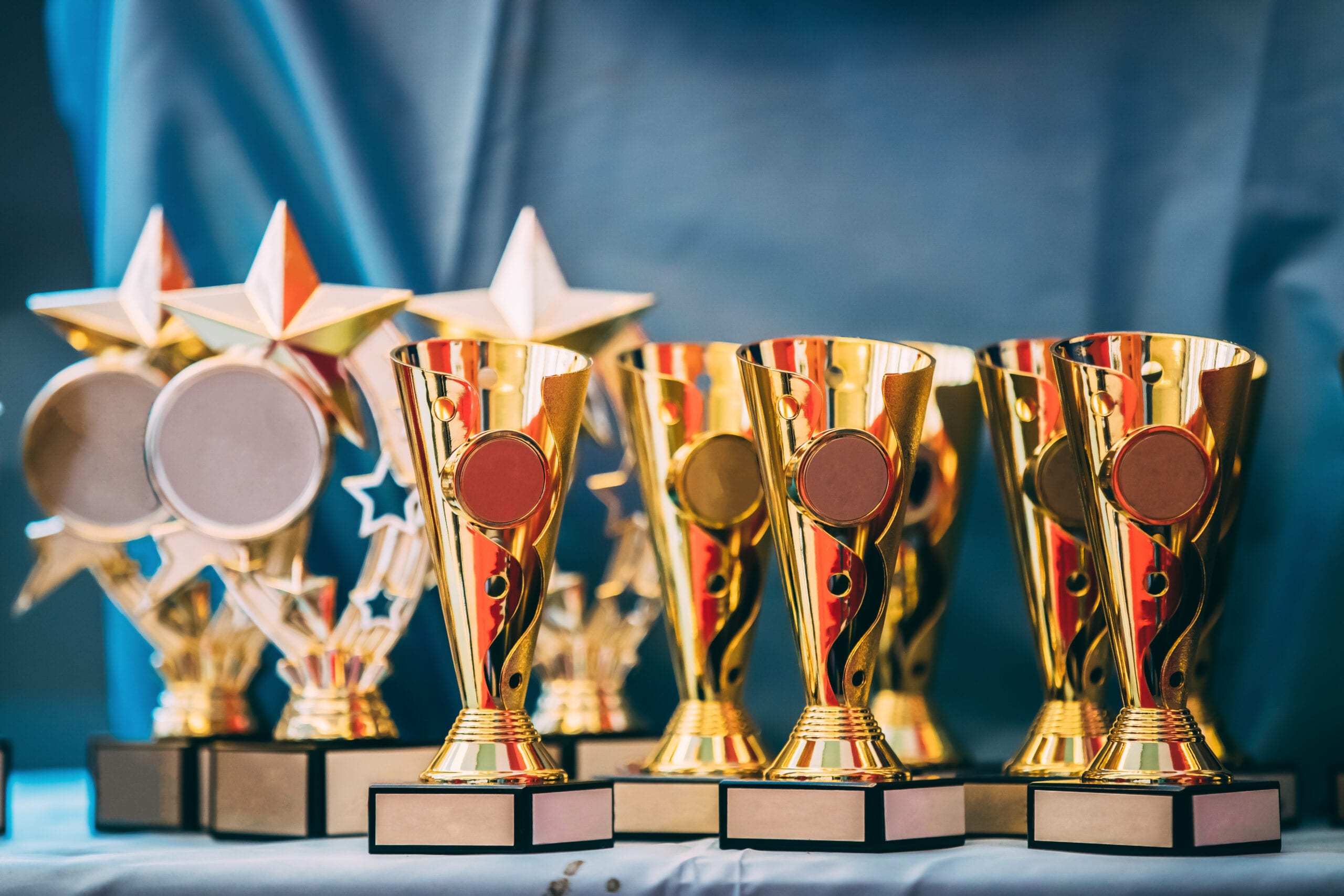 Different Champion Golden Trophy, Trophies. Winners Cups On Blue Cloth Background