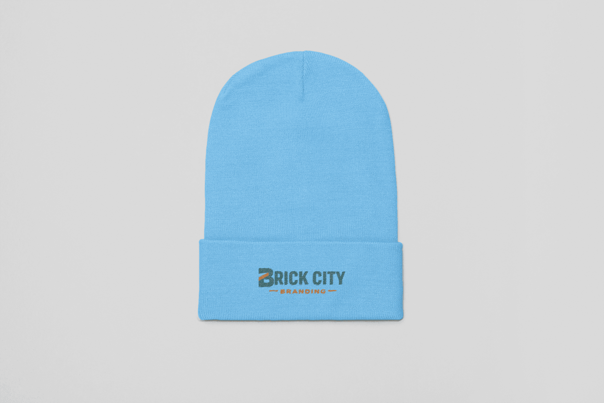 A light blue knit cuffed beanie featuring the Brick City Branding logo embroidered on the front cuff, centered against a neutral grey background.