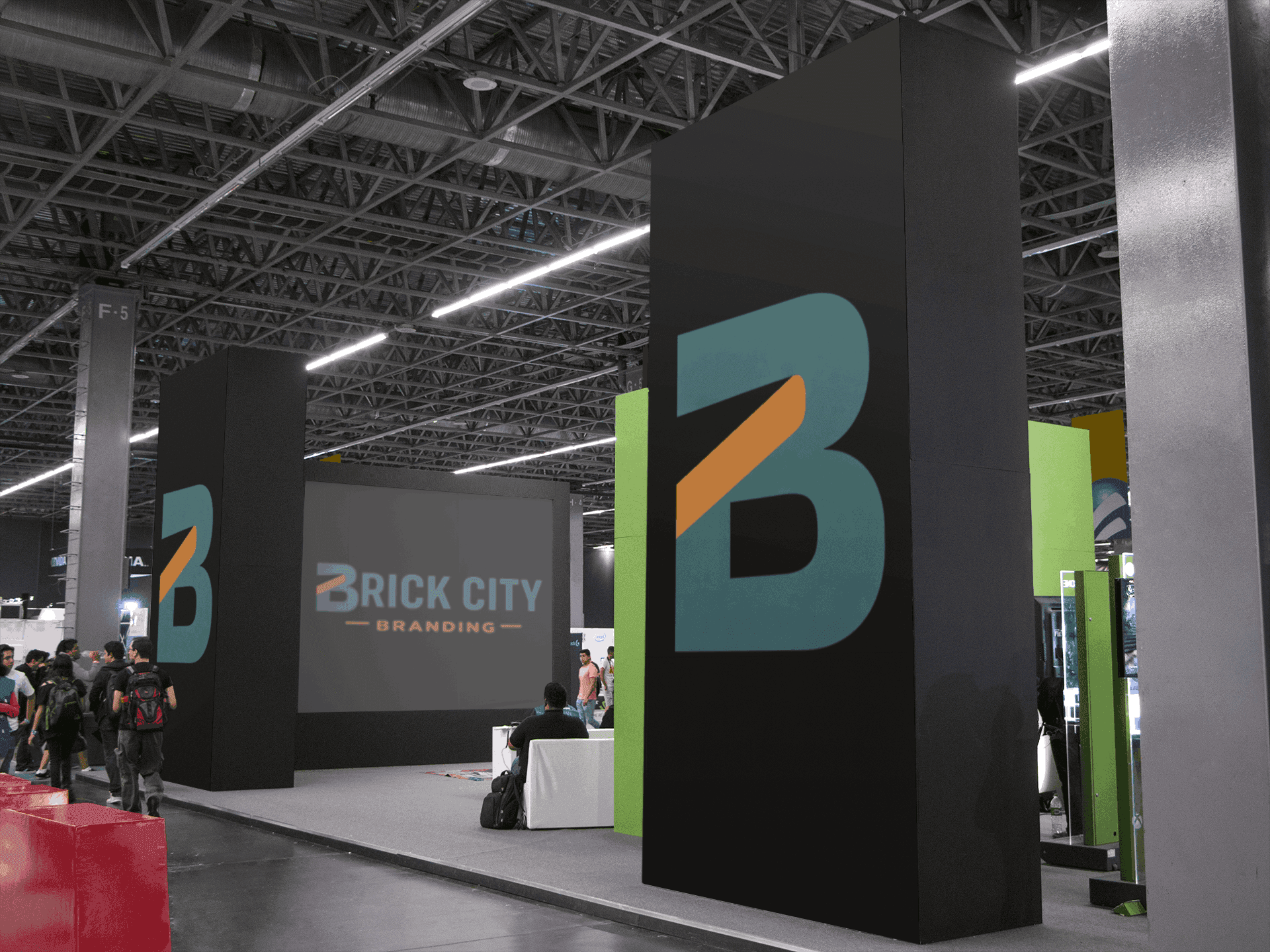 A large modern trade show exhibit for Brick City Branding featuring tall black monolith pillars with teal and orange logos and a large digital screen displaying the full brand name.