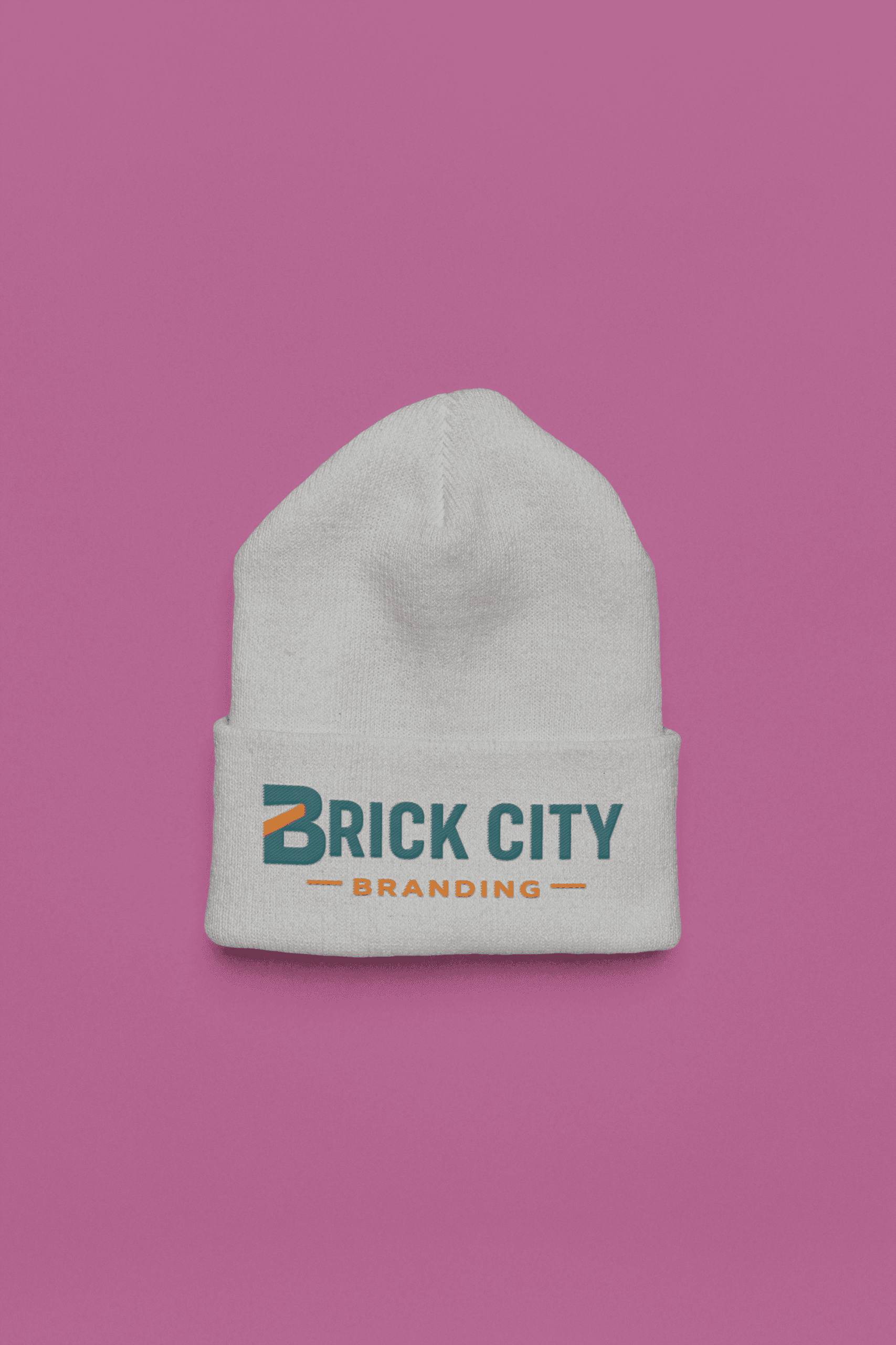 A white knit cuffed beanie featuring the Brick City Branding logo printed on the front cuff, centered against a solid purple background.