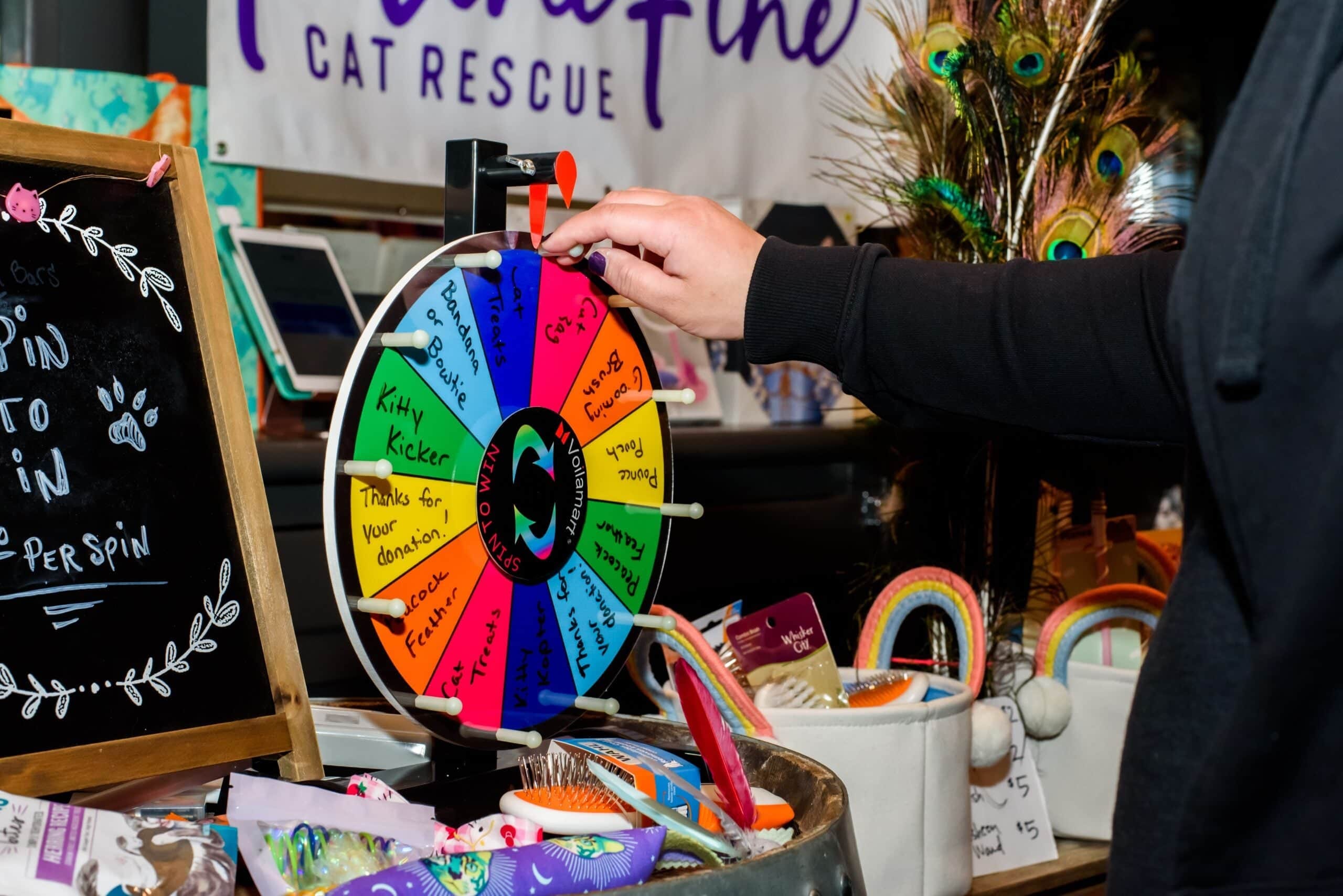 A close-up of a hand spinning a colorful prize wheel at a 