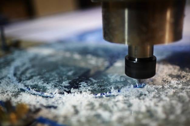 A close-up view of fine glass shavings and dust on a dark surface, reflecting light after a professional laser or rotary engraving process.