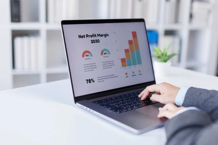 Close-up of a professional using a laptop to analyze a net profit margin dashboard with colorful growth charts, illustrating business financial strategy in Orlando, FL.